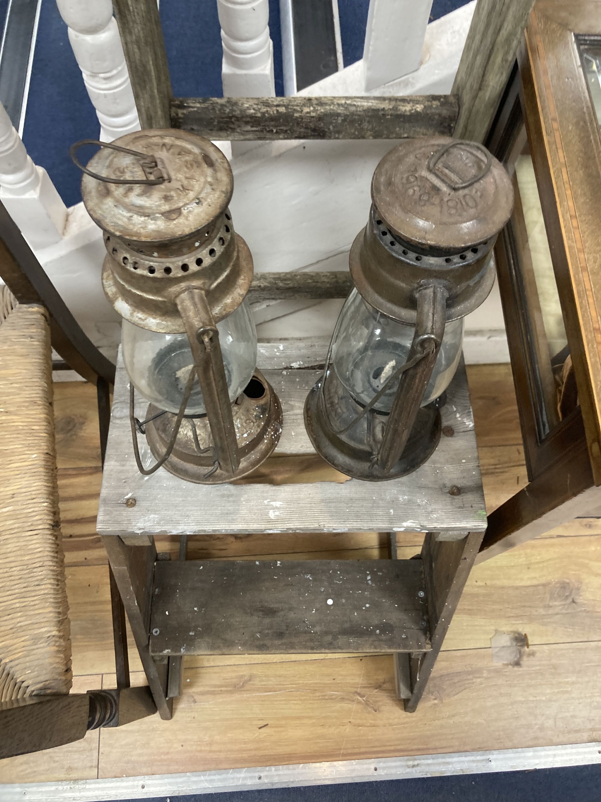 A rush seated beech elbow chair, a vintage five tread step ladder, a similar pine step stool and two oil lamps